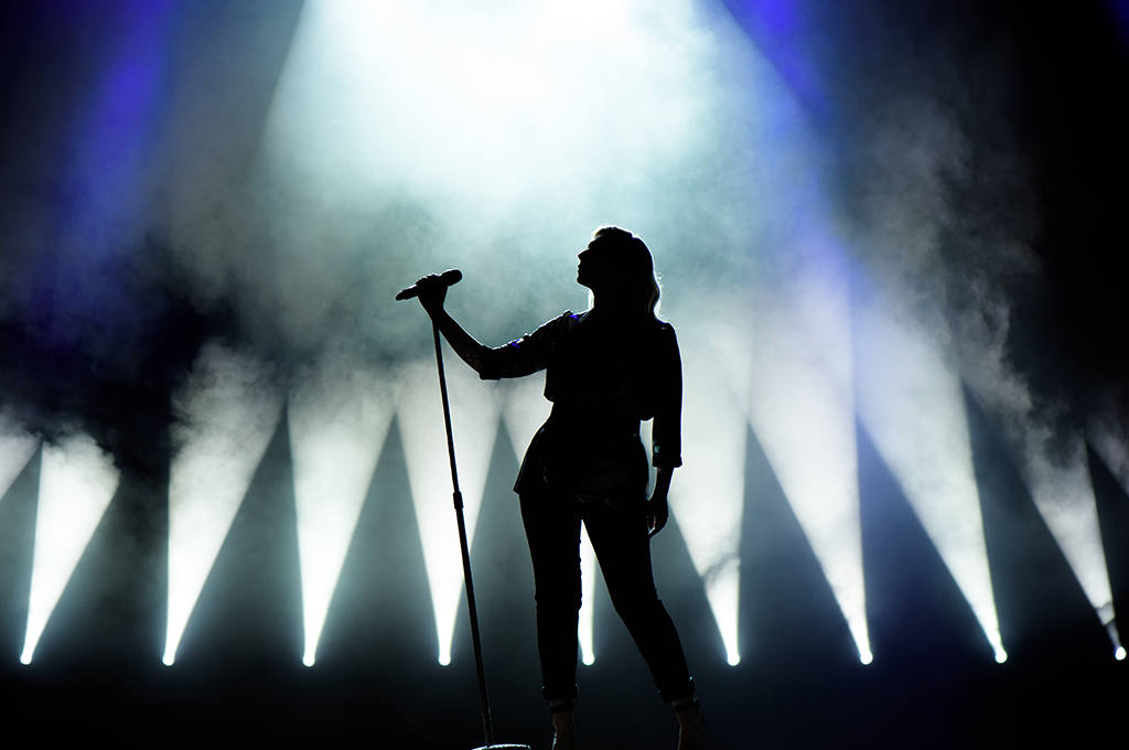 a singer's silhouette on stage with spotlights and smoke behind them