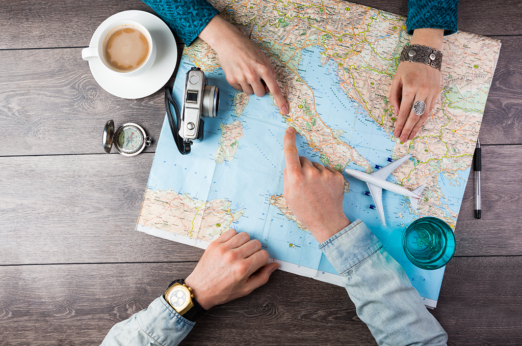 two people pointing at potential honeymoon destinations on a paper map
