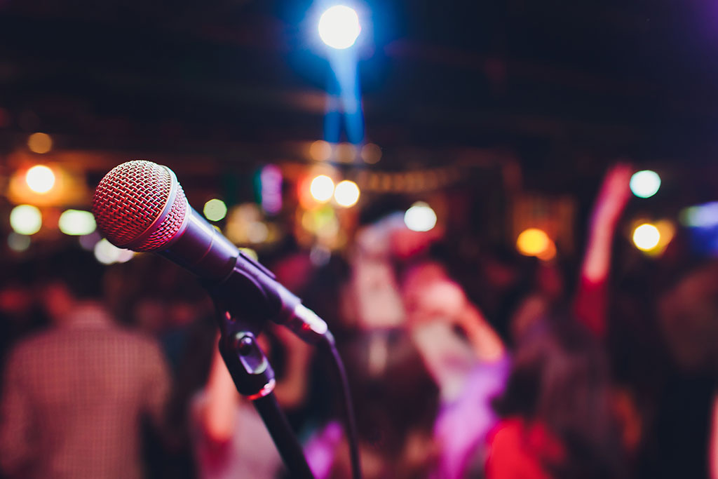 a microphone in focus in the foreground against a blurred background of a crowd of people