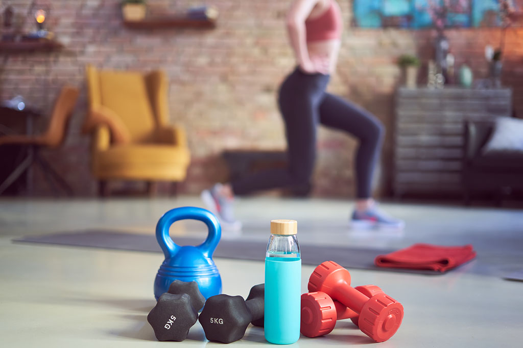 Woman exercising at home with exercise equipment in the front of the image.  