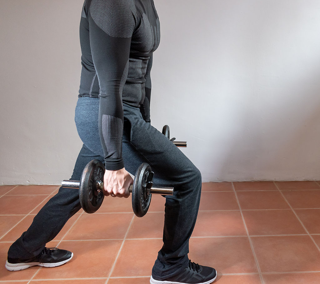 man doing exercise at home with dumbbells.