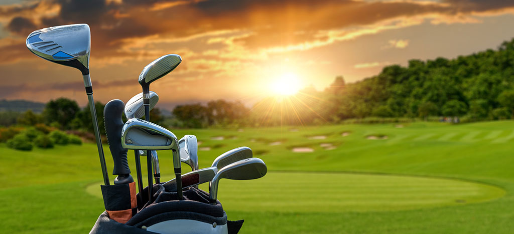golf clubs in a bag with a golf course in the background at sunset 