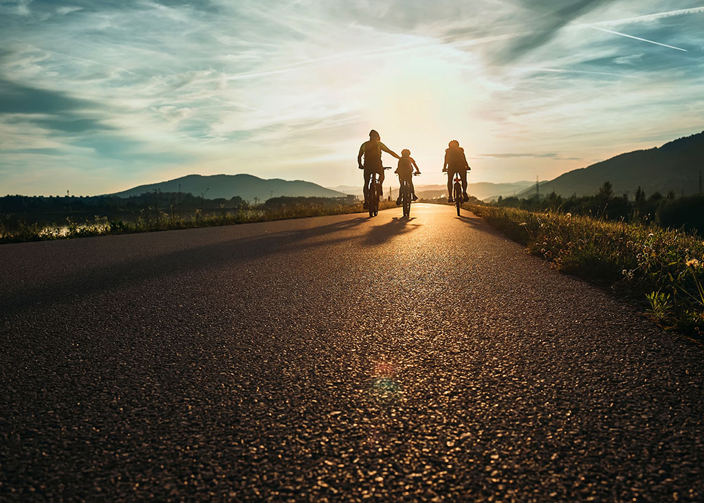 Cyclists family travelling on the road at sunset