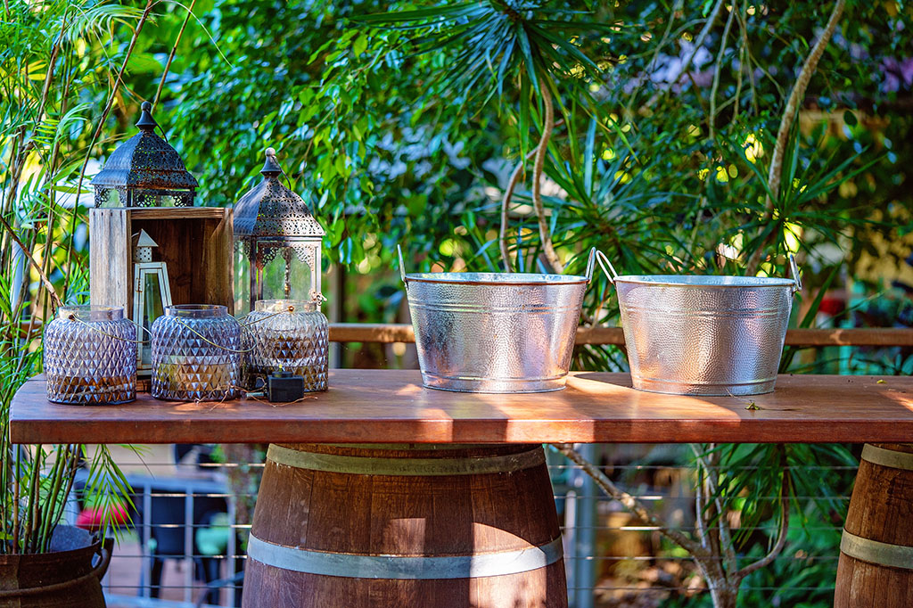 Wine buckets and candle holders on a wooden bar upheld with a barrel, bushland setting