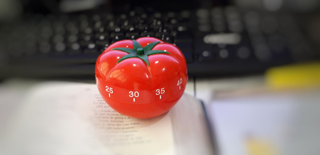 A tomato shaped timer next to a keyboard 