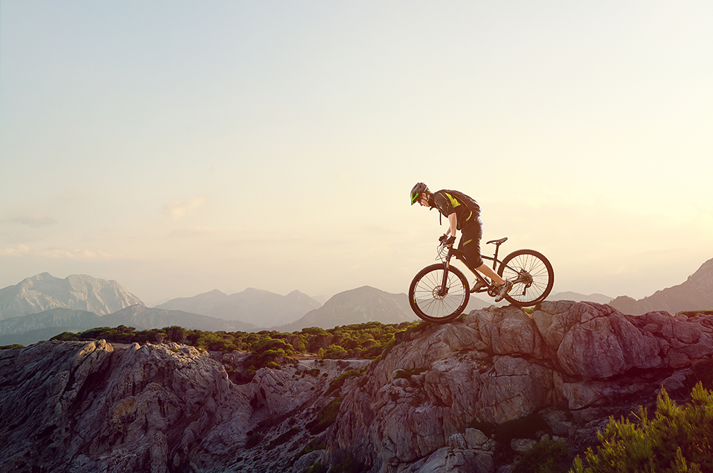 Cyclist on their bike on top of a rock 