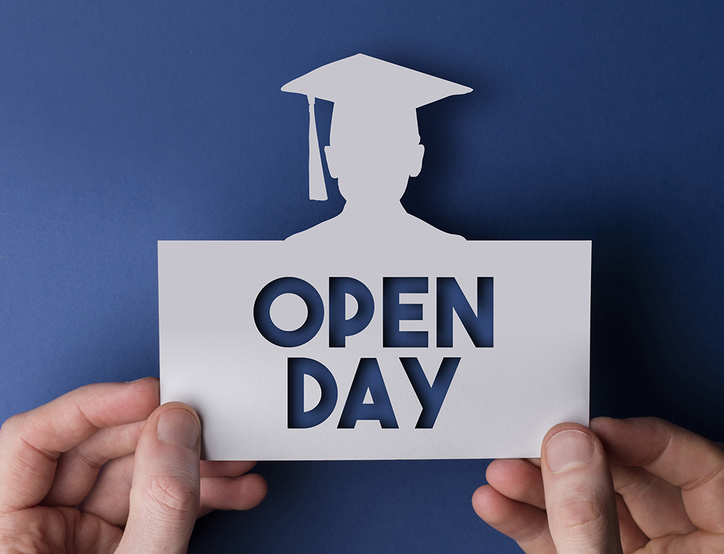 someone holding an envelope that says open day, that has a cut out of a graduate on the top