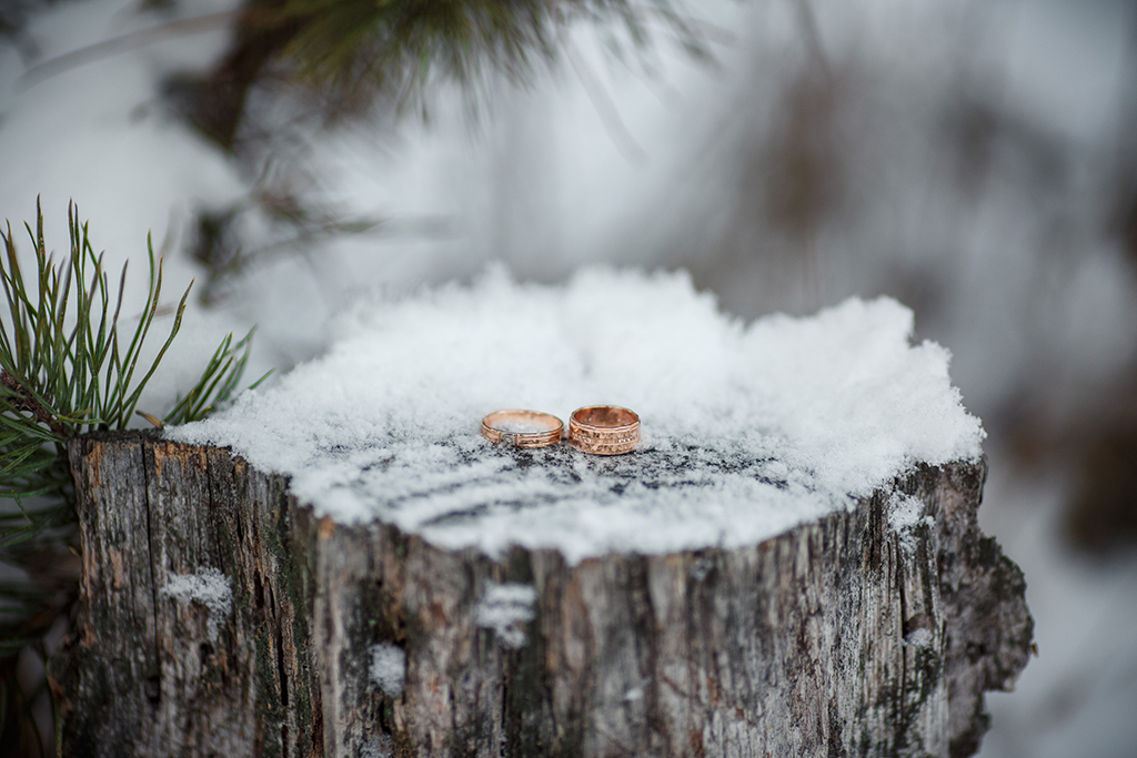two rings on a snowy treestump as some winter wedding photography ideas 