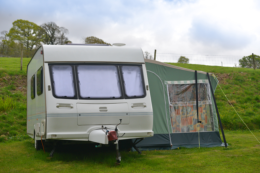 a towing caravan hitched up with a tent attached to the side 