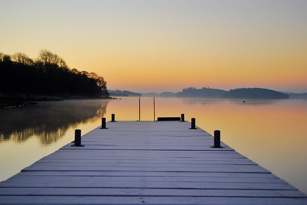 View from a jetty over Lough Erne on a calm frosty morning with a glowing orange sky