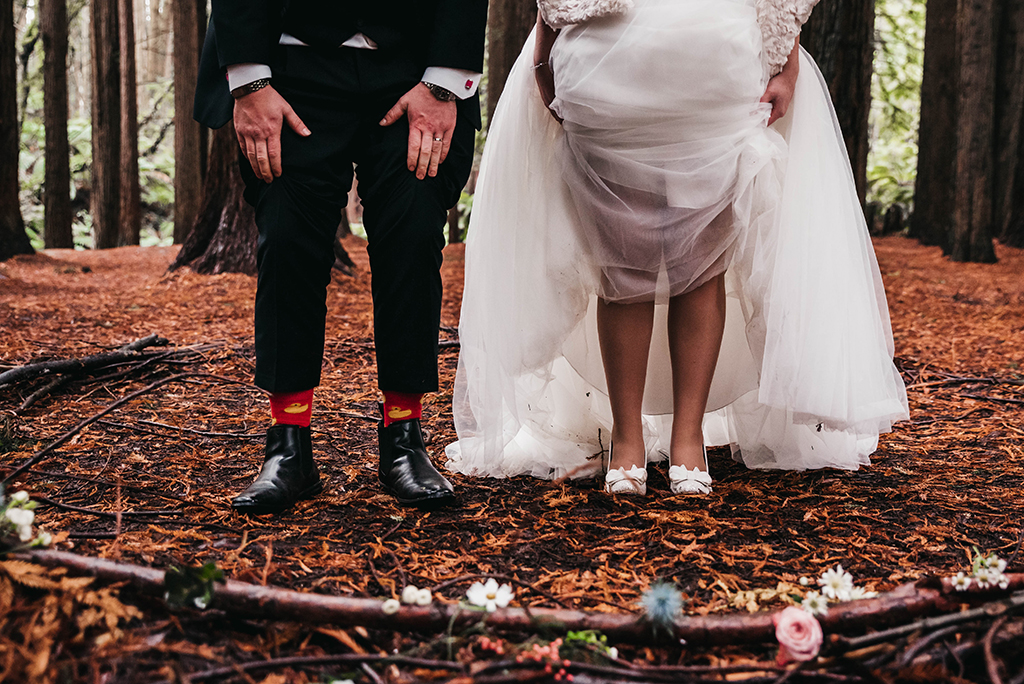 a picture of a pride and groom in the woods, taken by a wedding photographer, both showing their shoes 