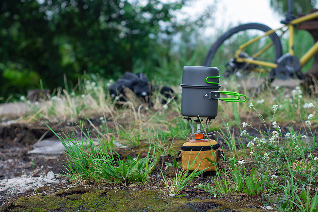 Tourist stove gas for camping and recreation on the background of a bicycle in nature