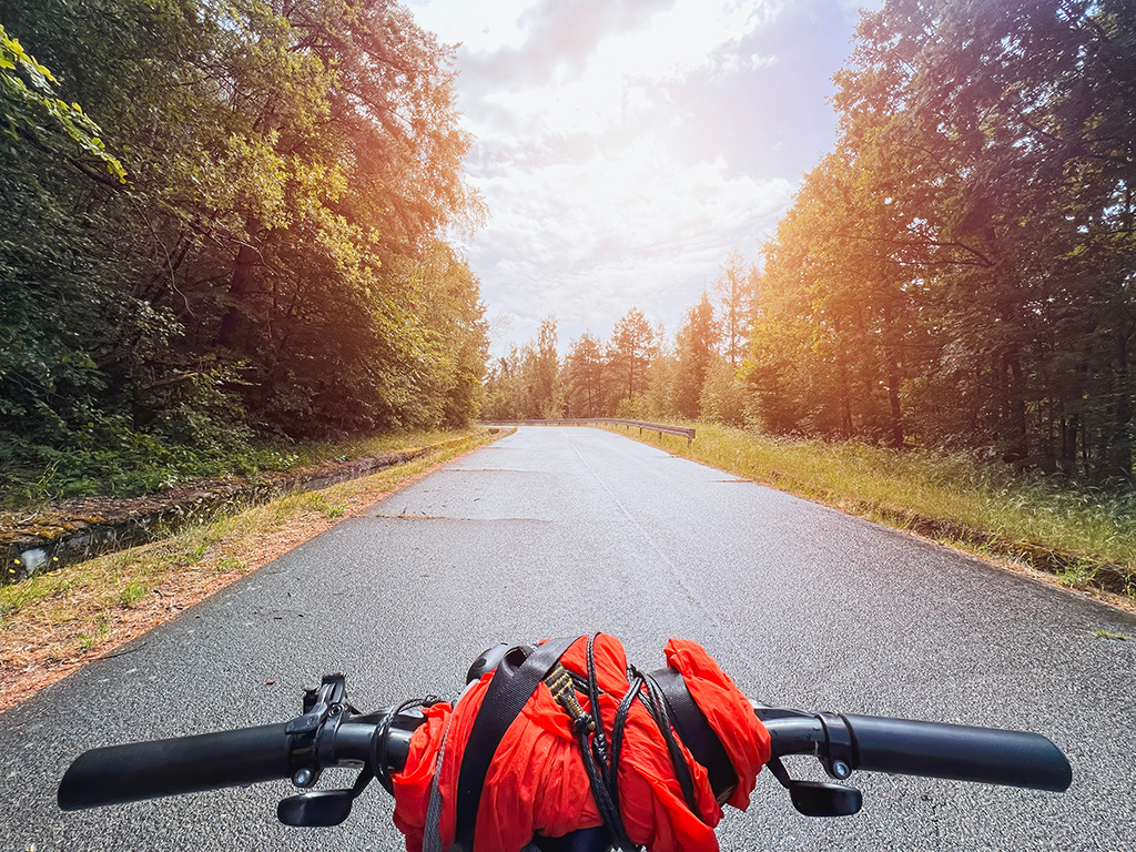 Bike trip to the forest. Journey on bicycle touring. Bike packing POV traveler journey with bicycle bags. Stylish bikepacking, bike, sportswear.