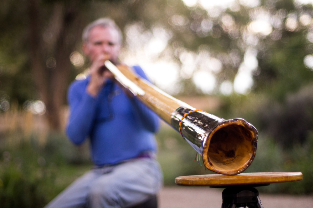 Man Plays Didgeridoo In Garden.