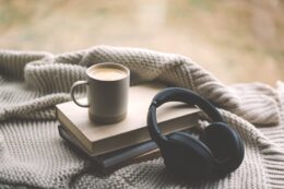 Pair Black Headphones Lies On Book.