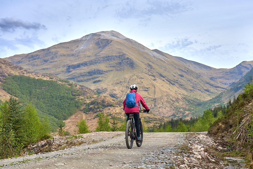 Woman riding her mountain bike in dramatic Scottish landscape.