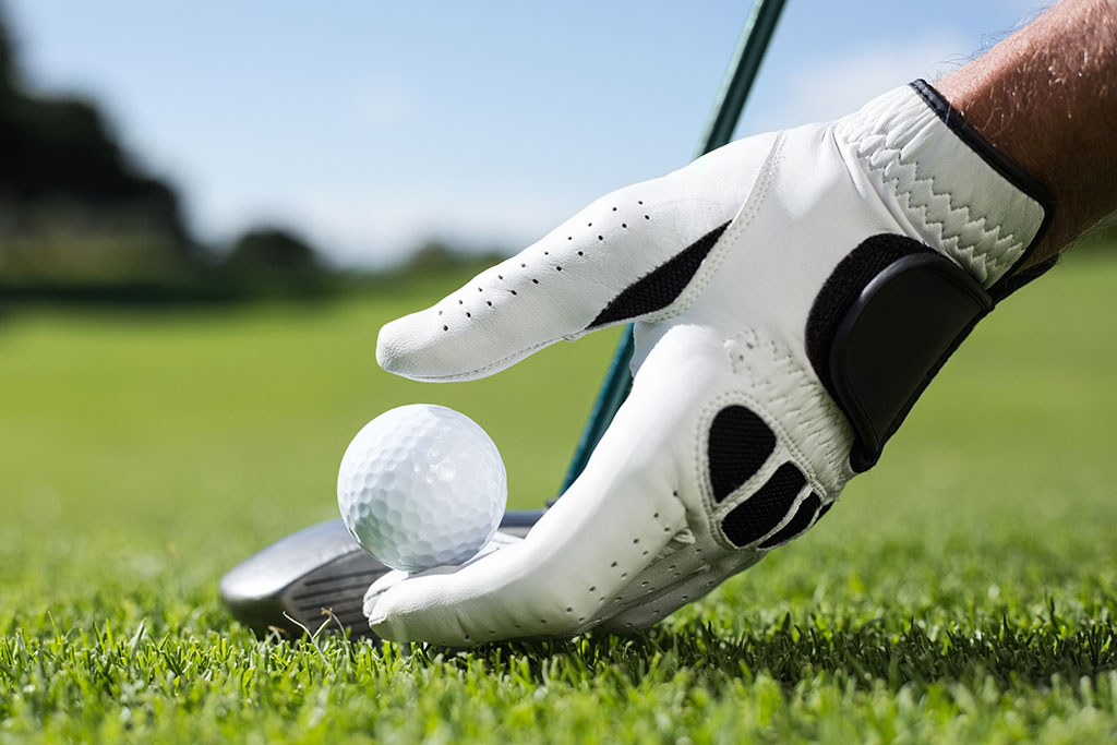 best golf brands golfer placing golf ball on a tee.